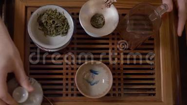 师傅用茶桌上的绿茶从盖湾的茶壶里<strong>倒热水</strong>